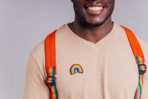 african american man student with backpack in studio smiling at the camera with a white smile