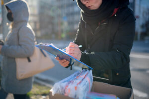 A person filling out information outside. This image is being used for PolicyWise's story "Establishing purpose and intention in youth homelessness data sharing."