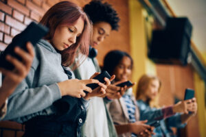 Youth and their friends using their smart phones in a hallway