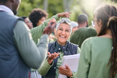 A woman standing among a group of people, gathering data. This image is being used by PolicyWise for Children & Families for their news story "Leading the shift from evidence to impact."
