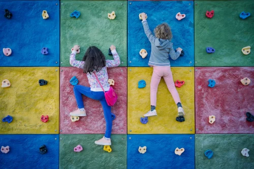 two children climbing a rock climbing wall. This image is being used for PolicyWise's news story "Turning strategy into action."